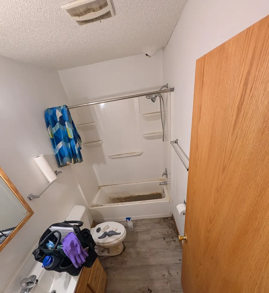 Dirty bathroom with a heavily stained bathtub and floors before professional deep cleaning in Fargo, ND