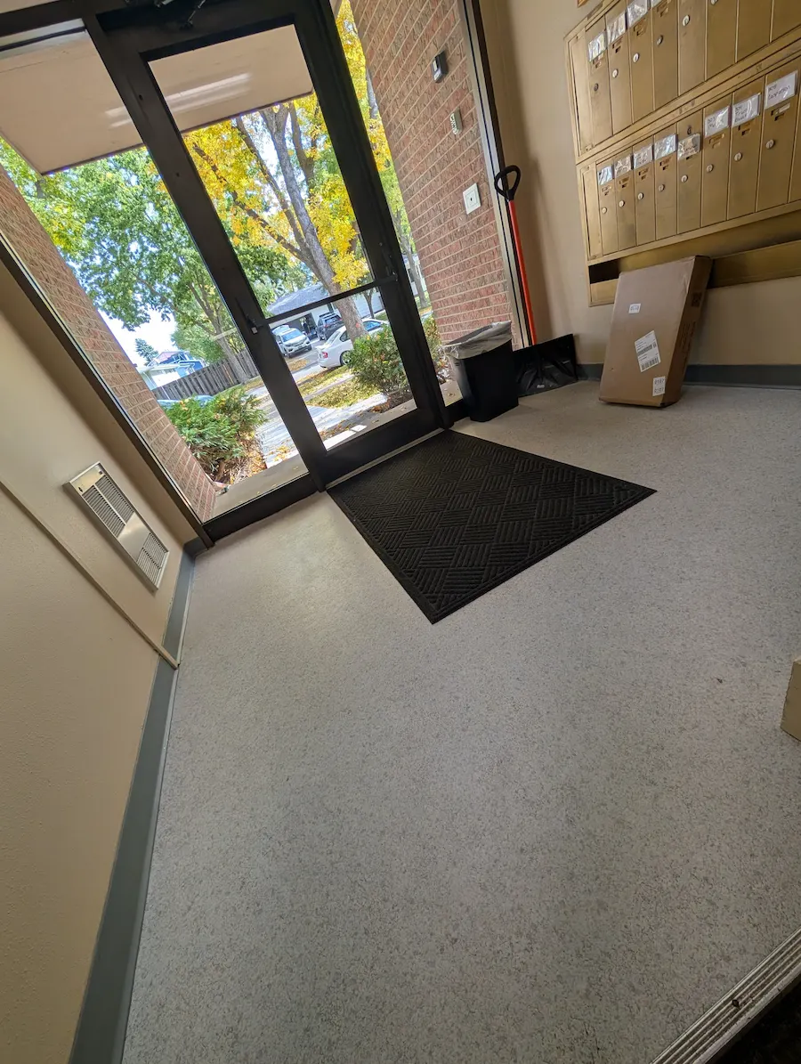 Apartment building entrance and shared mail area in Fargo, ND after commercial cleaning, with clean floors, removed debris, and a straightened entry mat